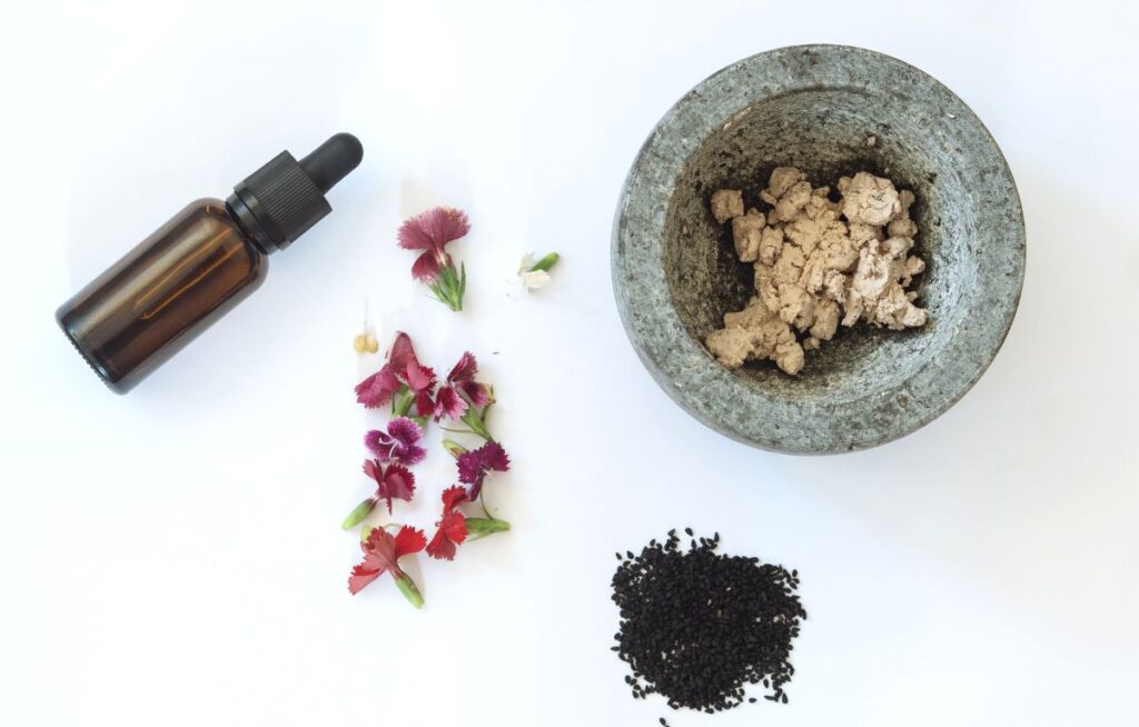 DIY face exfoliation ingredients, a vial of essential oil, and a mortar and pestle.