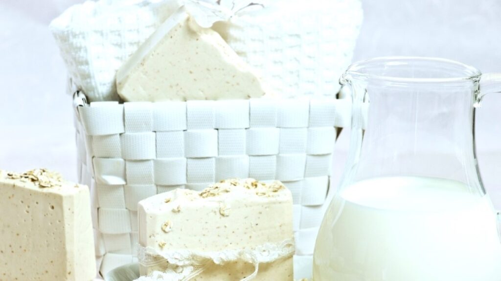 Oatmeal milk and honey soap with a pitcher of goat milk and a basket.